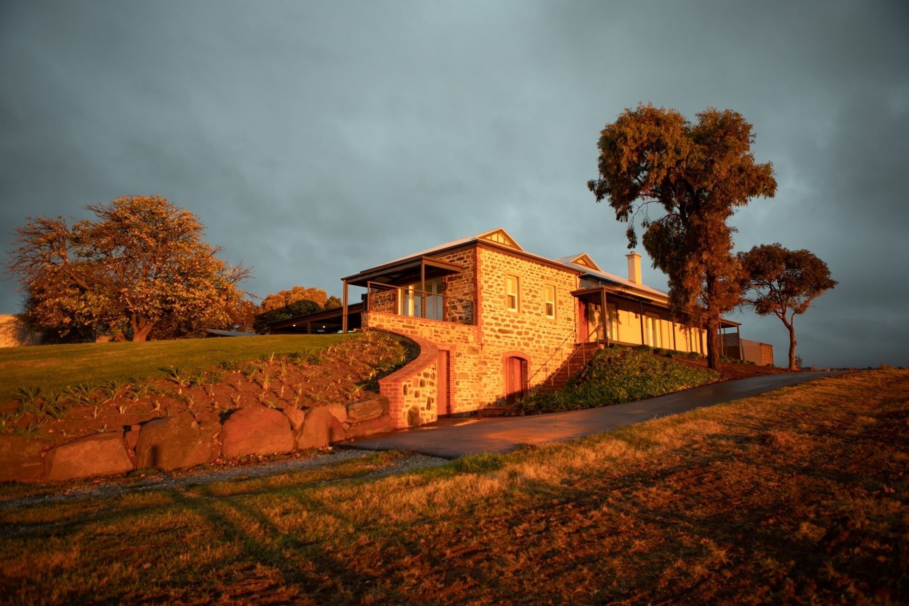 A stone house with a covered porch and a staircase leading up to it.