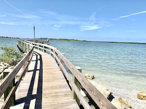 A wooden pier extending into calm water with a clear sky.