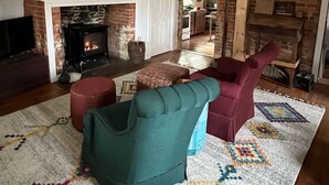 Una sala de estar acogedora con chimenea, vigas de madera y una pared de ladrillo rústico.