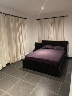 A bedroom with a bed, nightstands, and curtains.
