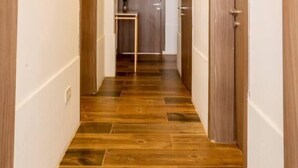Un couloir doté d’un plancher en bois, de murs blancs et d’une petite table sur laquelle est posée une plante.