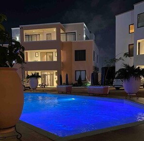 A modern building with a swimming pool at night.