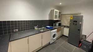A compact kitchen with a washing machine, a refrigerator, a microwave, and a sink. - Remarkable 2-Bed Apartment in Accra (Accra)