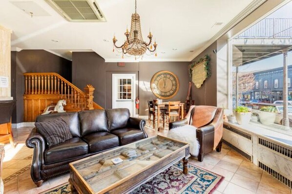 A living room with a leather sofa, a coffee table, a chandelier, and a large window with a city view.