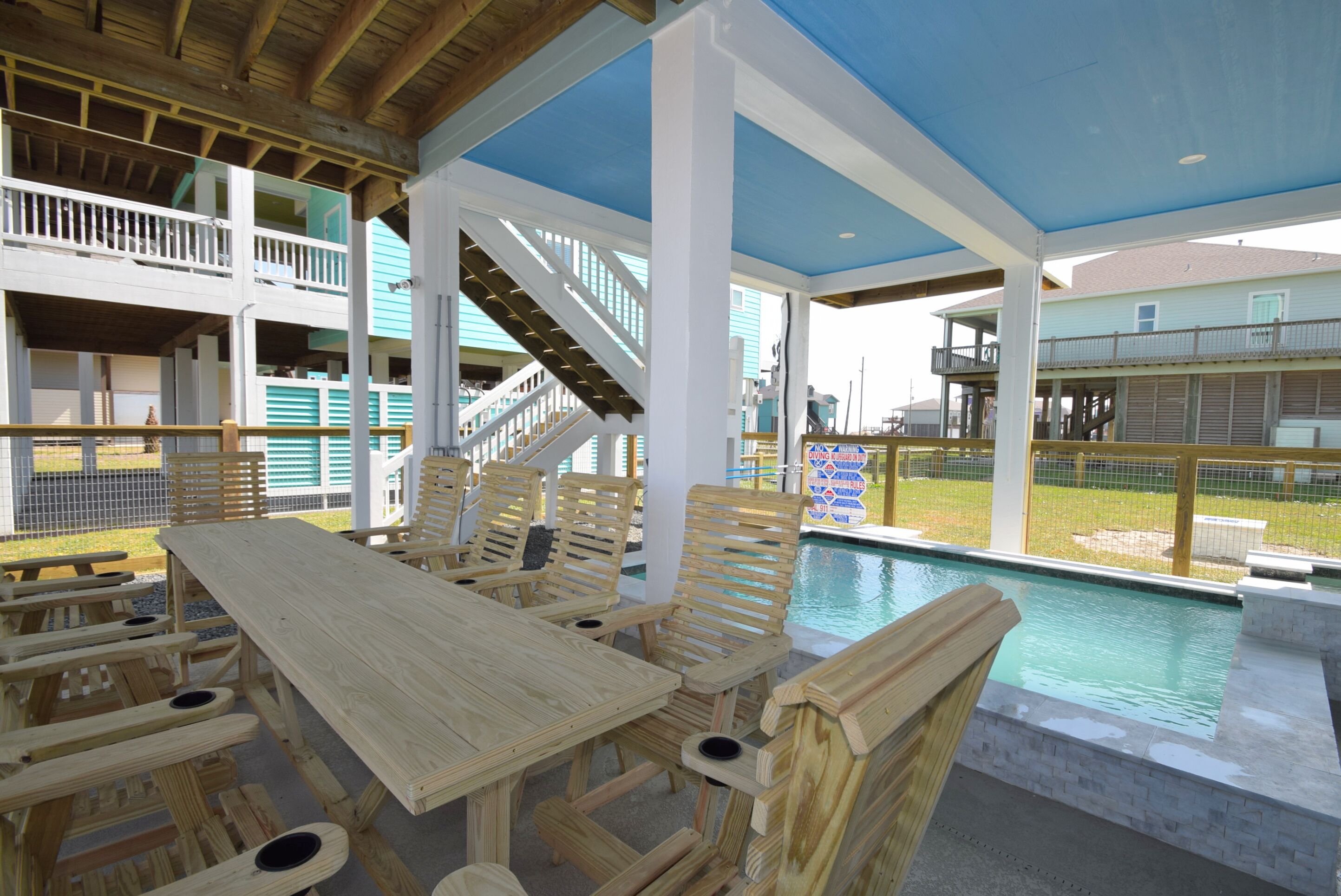 An outdoor pool area with wooden furniture and a covered seating area.