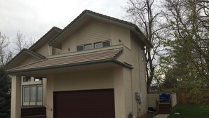 Ein zweistöckiges Haus mit Garage, überdachter Veranda und kleiner Terrasse.