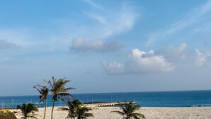 Una playa con palmeras, un muelle y cielo despejado.