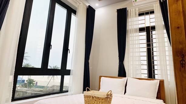Habitación de hotel con cama, ventana con cortinas, aire acondicionado y una lámpara en el techo.