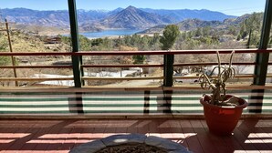 Uma varanda com vista para montanhas e um lago.