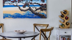 Ein Essbereich mit einem runden Tisch, Stühlen und einem Bild von einem Baum am Meer.