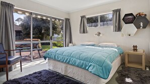 Ein Schlafzimmer mit einem großen Bett, einem Sessel, einem Schreibtisch und Blick ins Freie.