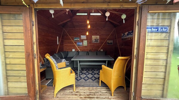 A cozy wooden cabin interior with a sofa, two yellow chairs, a dining table, and a rug. - Alte Schule Niebüll (Niebüll)