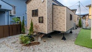 A mobile home with a brick exterior, a small window, and a logo on the side. - Dio (Fujikawaguchiko)