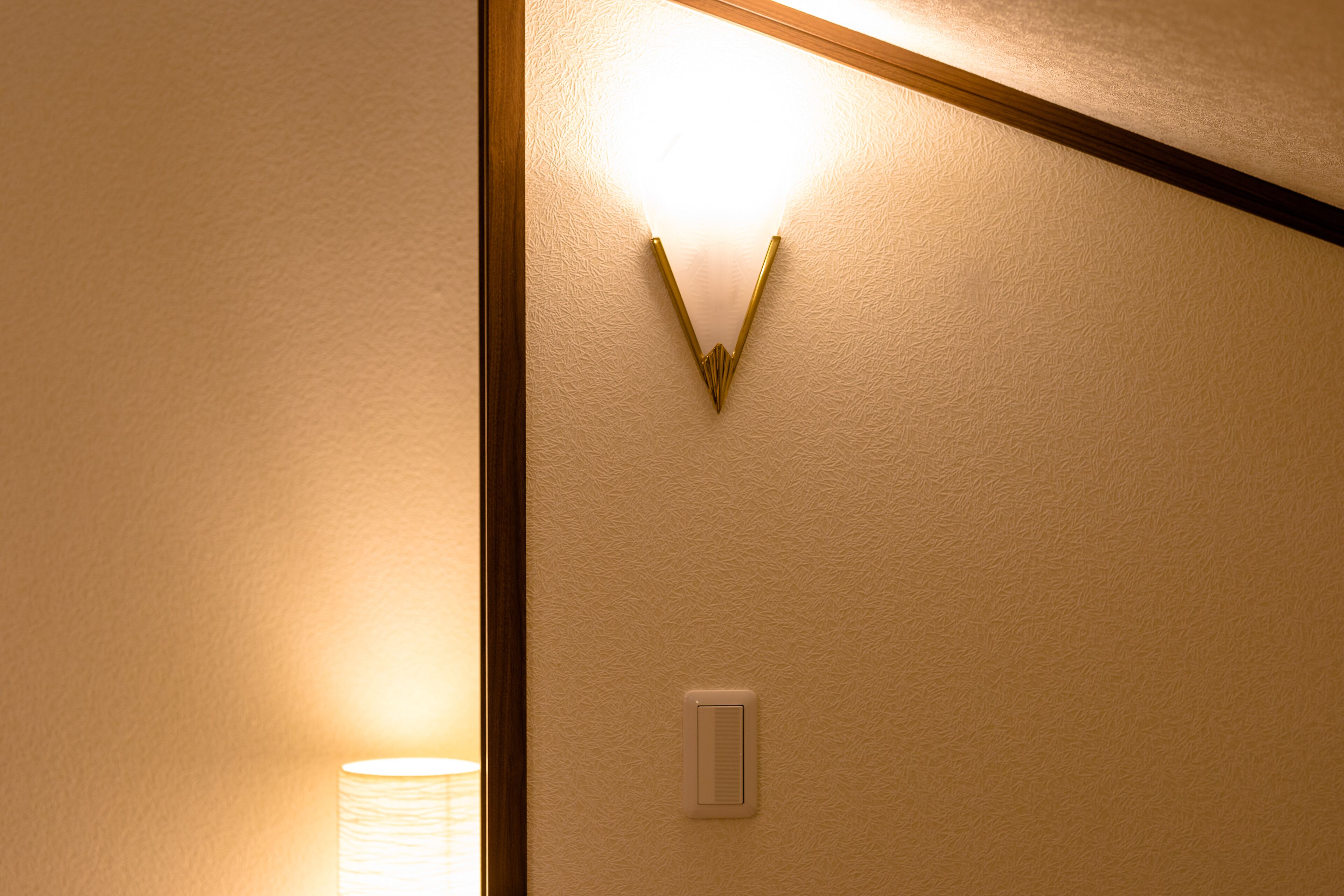 Una pared con textura y una lámpara con diseño triangular.