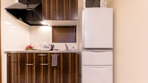 A compact kitchen with wooden cabinets, a white refrigerator, and a built-in oven. - Dio (Fujikawaguchiko)
