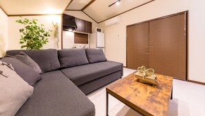 A modern living room with a sectional sofa, a wooden coffee table, and a sliding door closet. - Dio (Fujikawaguchiko)
