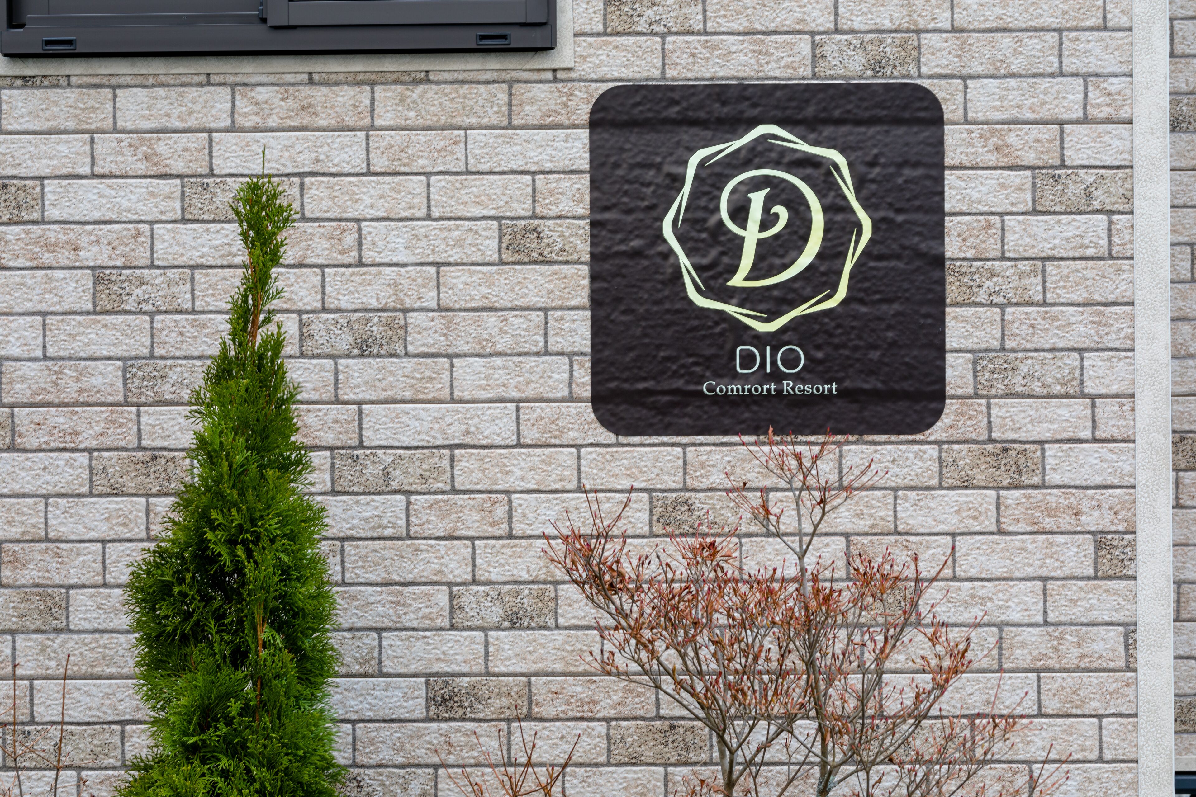 A sign for "DIO Comfort Resort" on a brick wall.