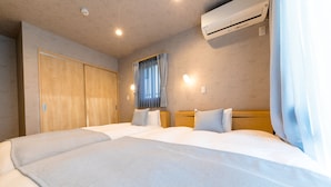 Et hotelværelse med to senge, et klædeskab, en aircondition og et vindue med gardiner.