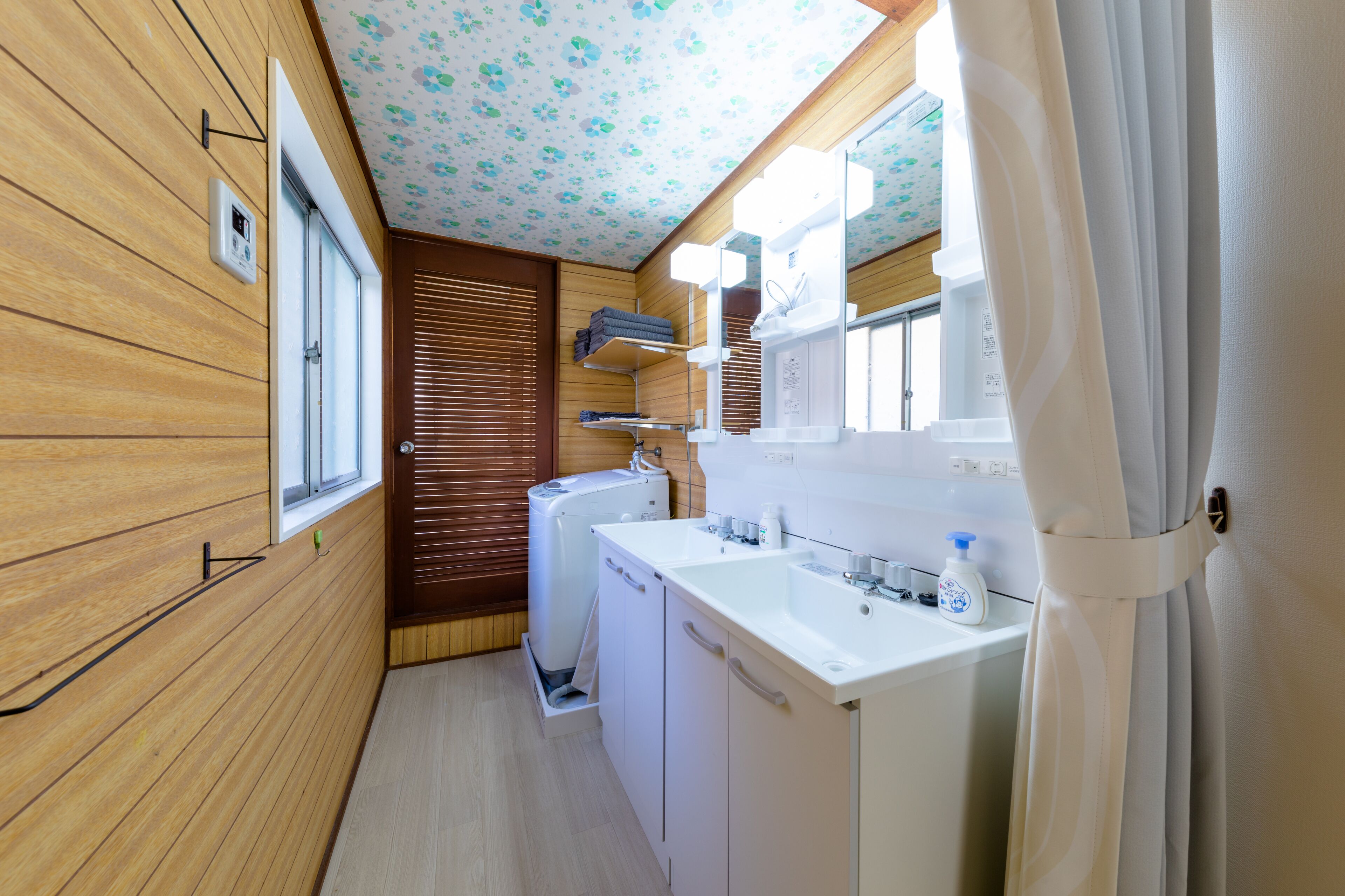 A compact, well-lit bathroom with wooden walls, a white sink, and a window.
