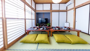 A traditional Japanese room with tatami flooring, a low table set for dining, and a television in the background. - RAKUWA Bettei (Fujikawaguchiko)