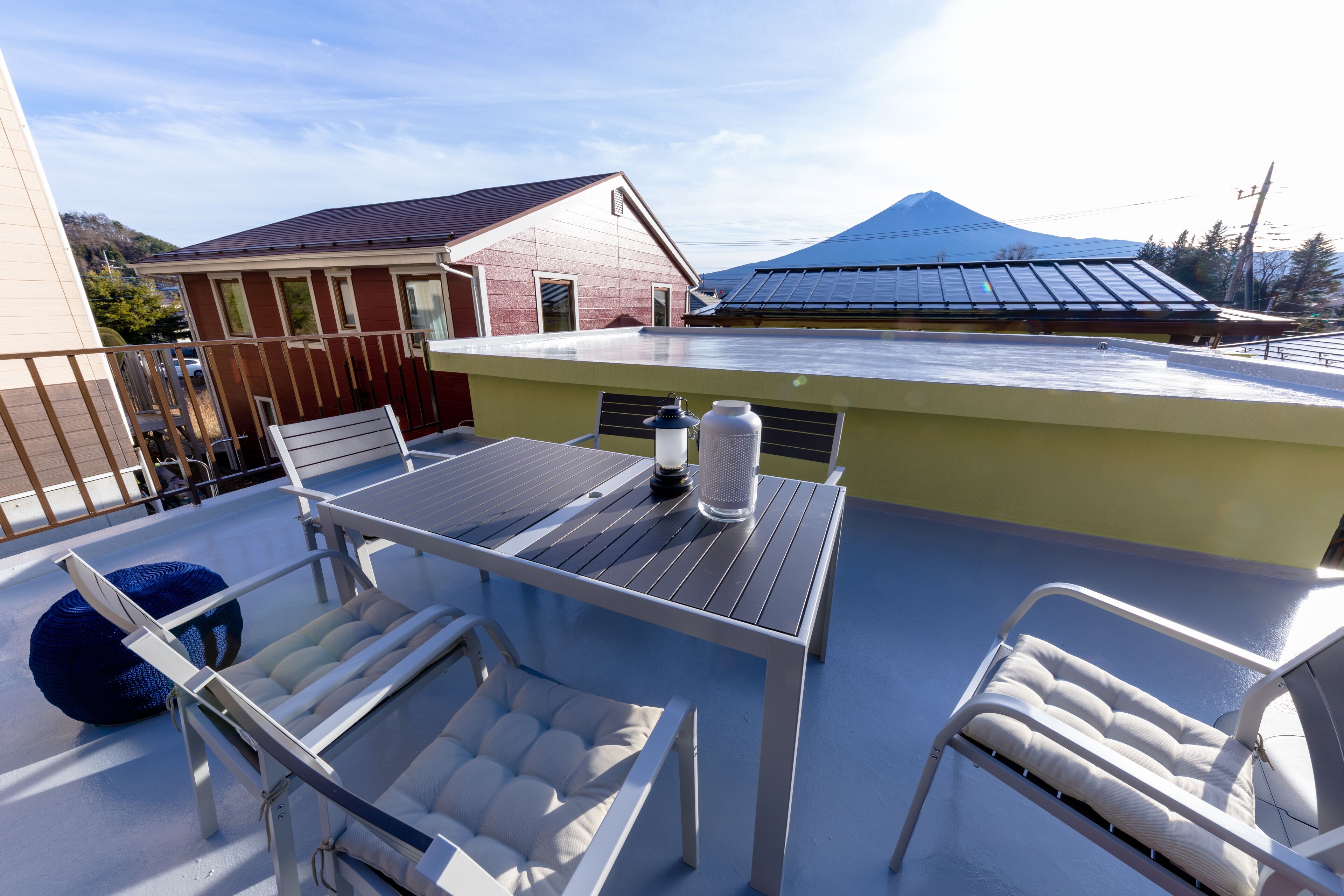 A rooftop terrace with a table and chairs, solar panels, and a mountain in the background.