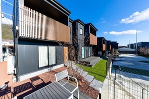 A row of modern residential buildings with balconies, a well-maintained lawn, and a clear sky. - Mt. Fuji Resort Club-YUI- (Fujikawaguchiko)