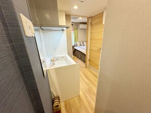 A compact kitchen with a modern design, a built-in oven, and a small sink. - Shinjuku Warm House (Tokyo)