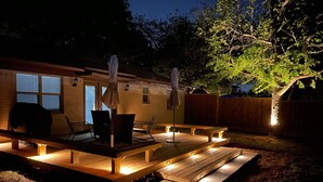A wooden deck with benches and umbrellas, surrounded by a wooden fence and trees.