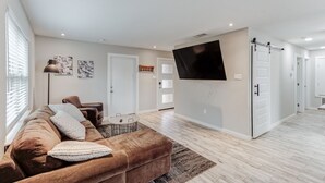 A modern living room with a brown sofa, a coffee table, and a flat-screen TV mounted on the wall.