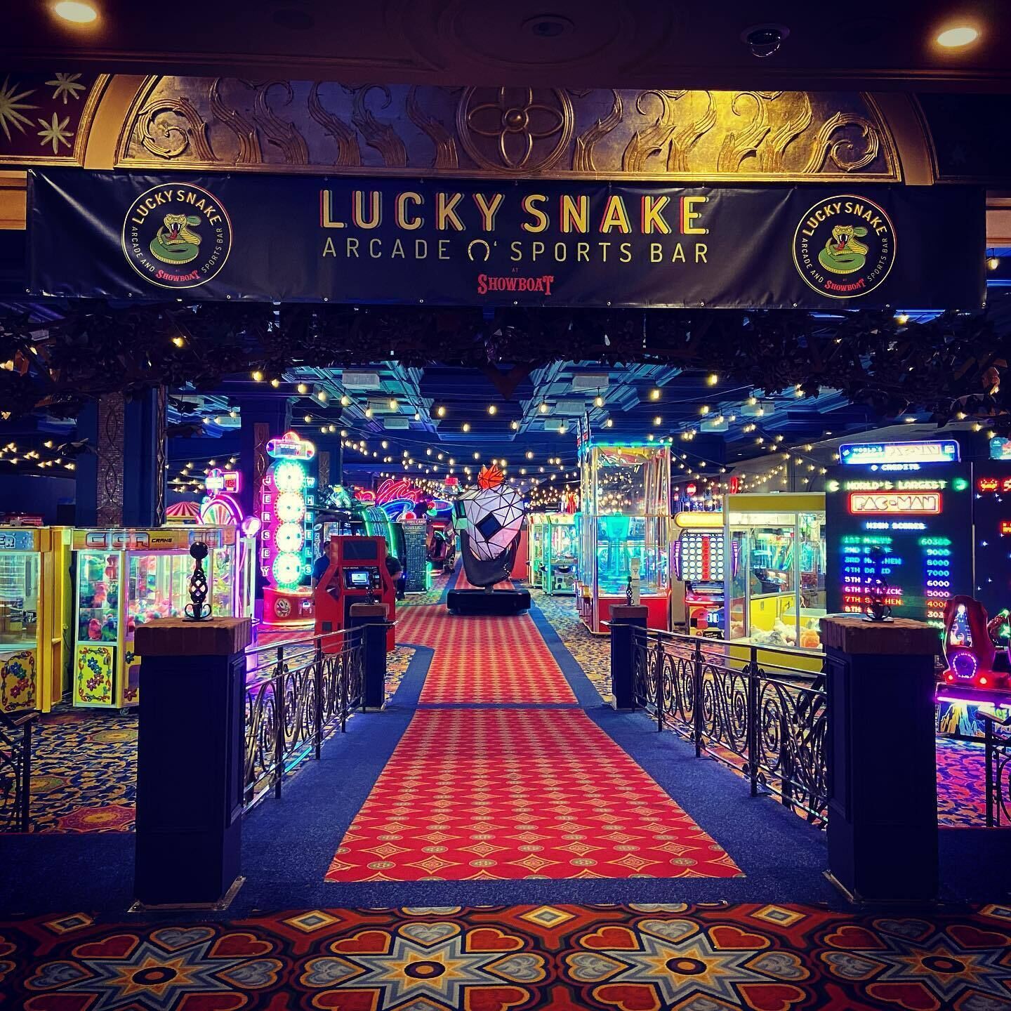 Un salón de juegos con una alfombra roja que conduce a varias máquinas recreativas.