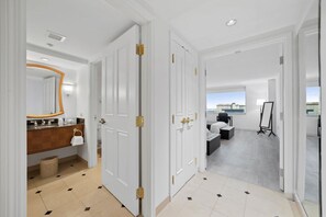 A hotel room with a bathroom, a desk, and a view of the city.