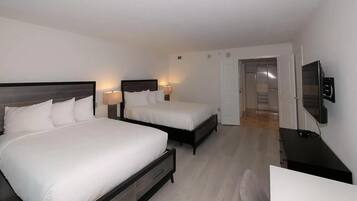 Two single beds with bedside tables and lamps, a flat-screen TV, and a bright, airy feel.