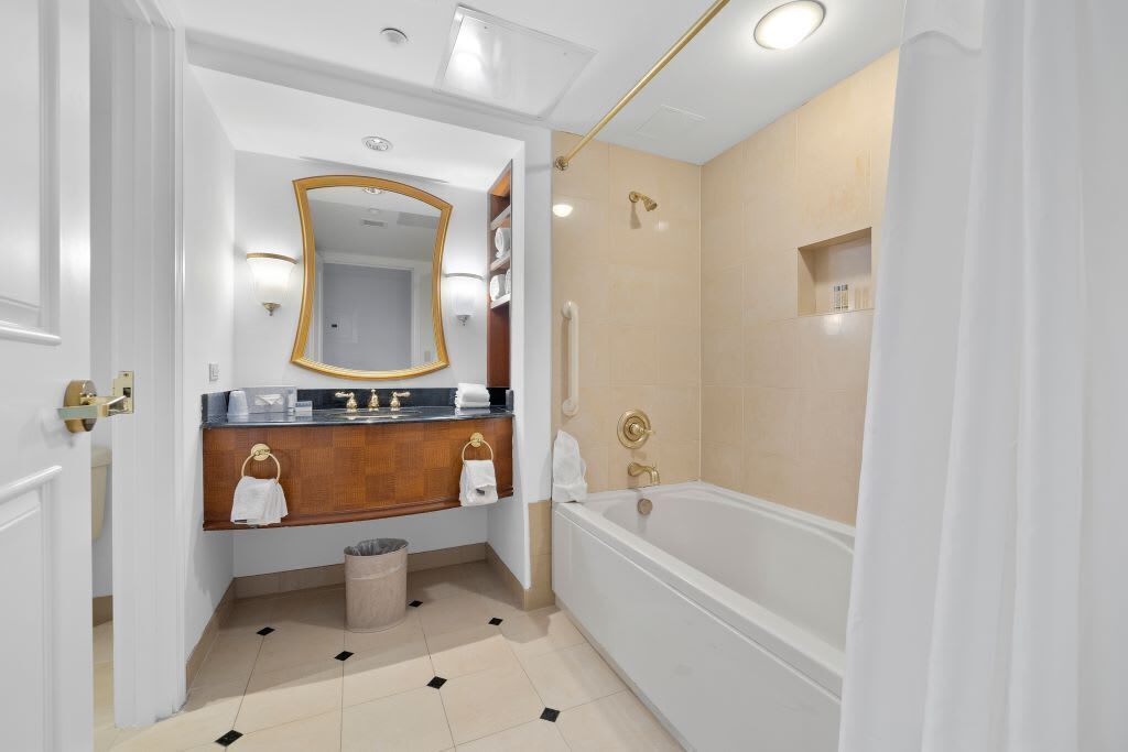 A modern bathroom with a large mirror, a bathtub, and a shower area.