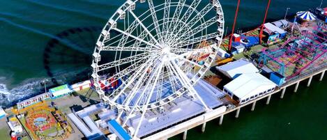 Une jetée sur laquelle se trouvent une grande roue, un carrousel et diverses attractions.