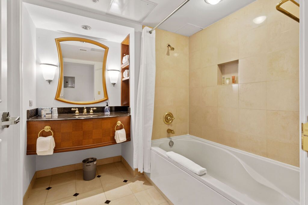 A modern bathroom with a vanity, a large mirror, a bathtub, and a shower area.