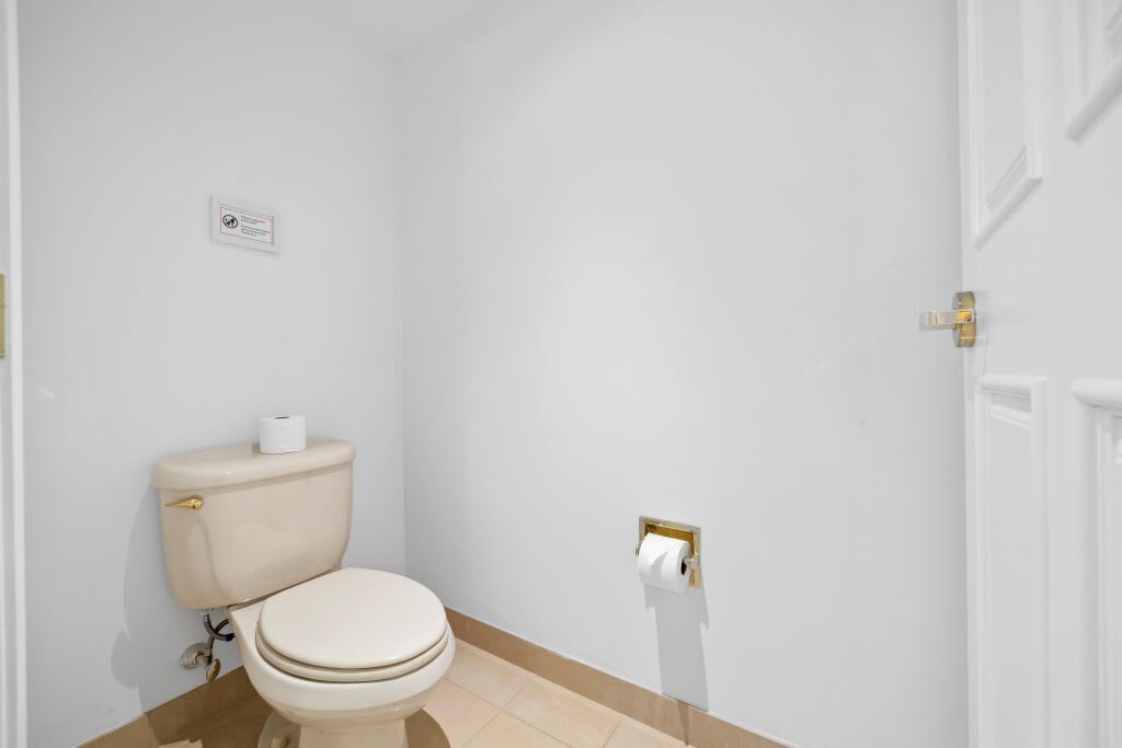Une petite salle de bain propre, équipée de toilettes, d’un distributeur d’essuie-tout et d’un panneau fixé au mur.