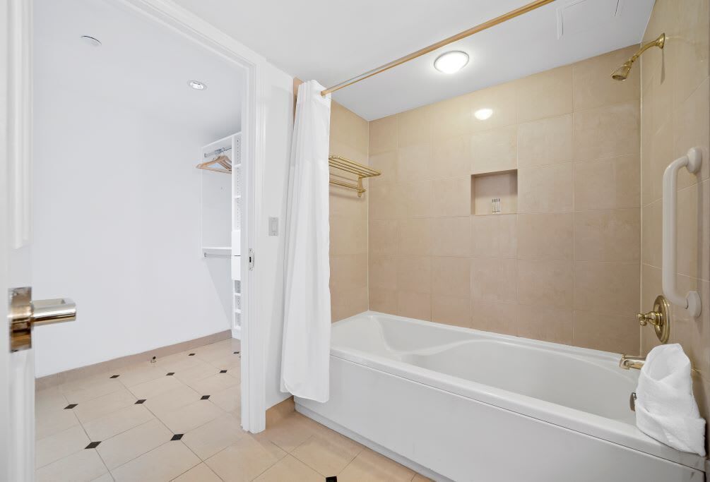A modern bathroom with a bathtub, a shower area, and a white door.