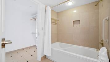 A modern bathroom with a bathtub, a shower area, and a white door.