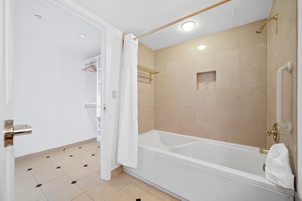A modern bathroom with a bathtub, a shower area, and a white door.