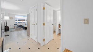 Un couloir avec des portes blanches, un coin repas avec une table et des chaises, et une vue sur un bâtiment à l’extérieur.