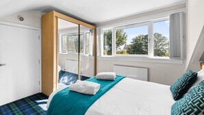 A bedroom with a bed, a window, and a door. - The Albatross - 3 bed Carnoustie Classic (Angus)