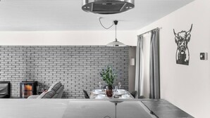 A modern dining area with a brick wall, a table set for two, and a pendant light above. - The Albatross - 3 bed Carnoustie Classic (Angus)