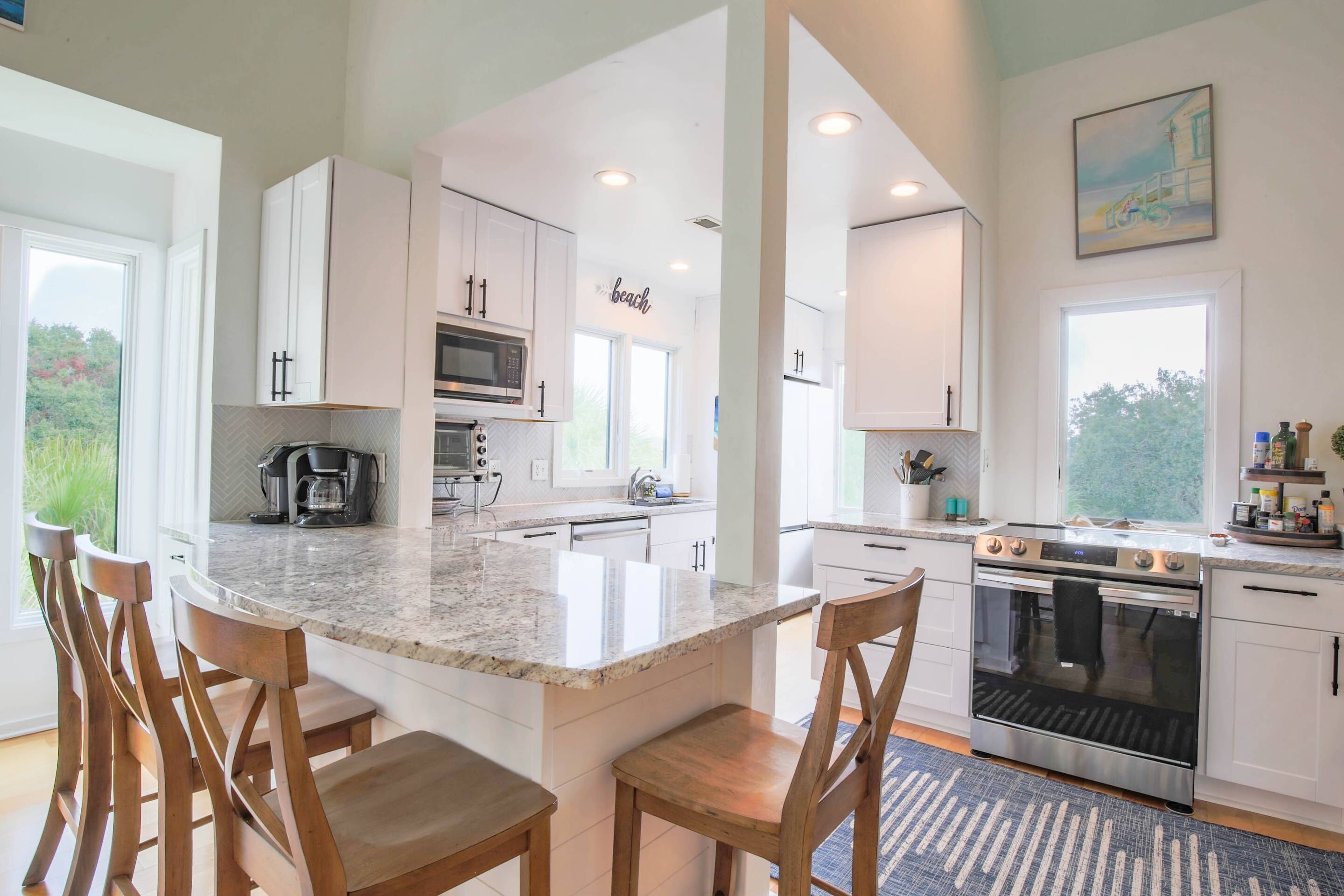 A modern kitchen with white cabinets, a granite countertop, and a central island with bar stools.