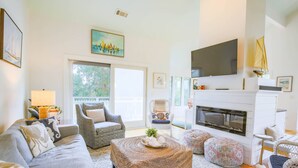 A living room with a sofa, armchair, ottoman, fireplace, and a television mounted above the fireplace. - 2 Minute Walk to Beach; Access to Community Pool and Pickle Ball, Basketball & Tennis Courts (Isle of Palms)