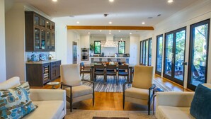 A spacious living area with a dining table, comfortable seating, and a kitchen in the background. - Newly Constructed, Custom Built Home w/ Mesmerizing Marsh Views, 2 Master Suites & Outdoor Spaces (Kiawah Island)
