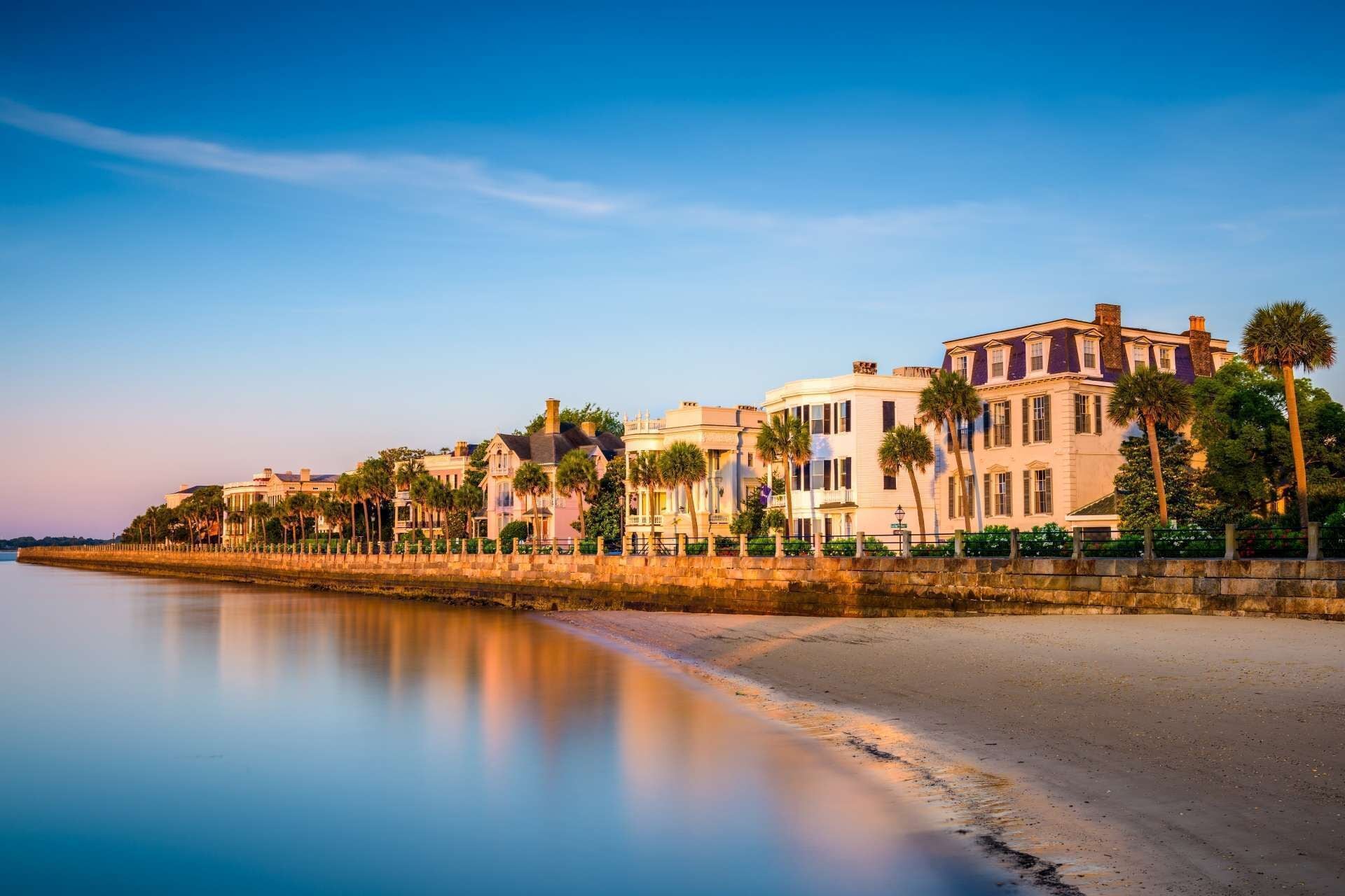 Un hotel frente al mar con una hilera de edificios a lo largo de la costa, con balcones y palmeras.