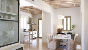 Une cuisine moderne avec un coin repas, dotée d’un plafond en bois, d’un réfrigérateur encastré et d’une table à manger avec des chaises.
