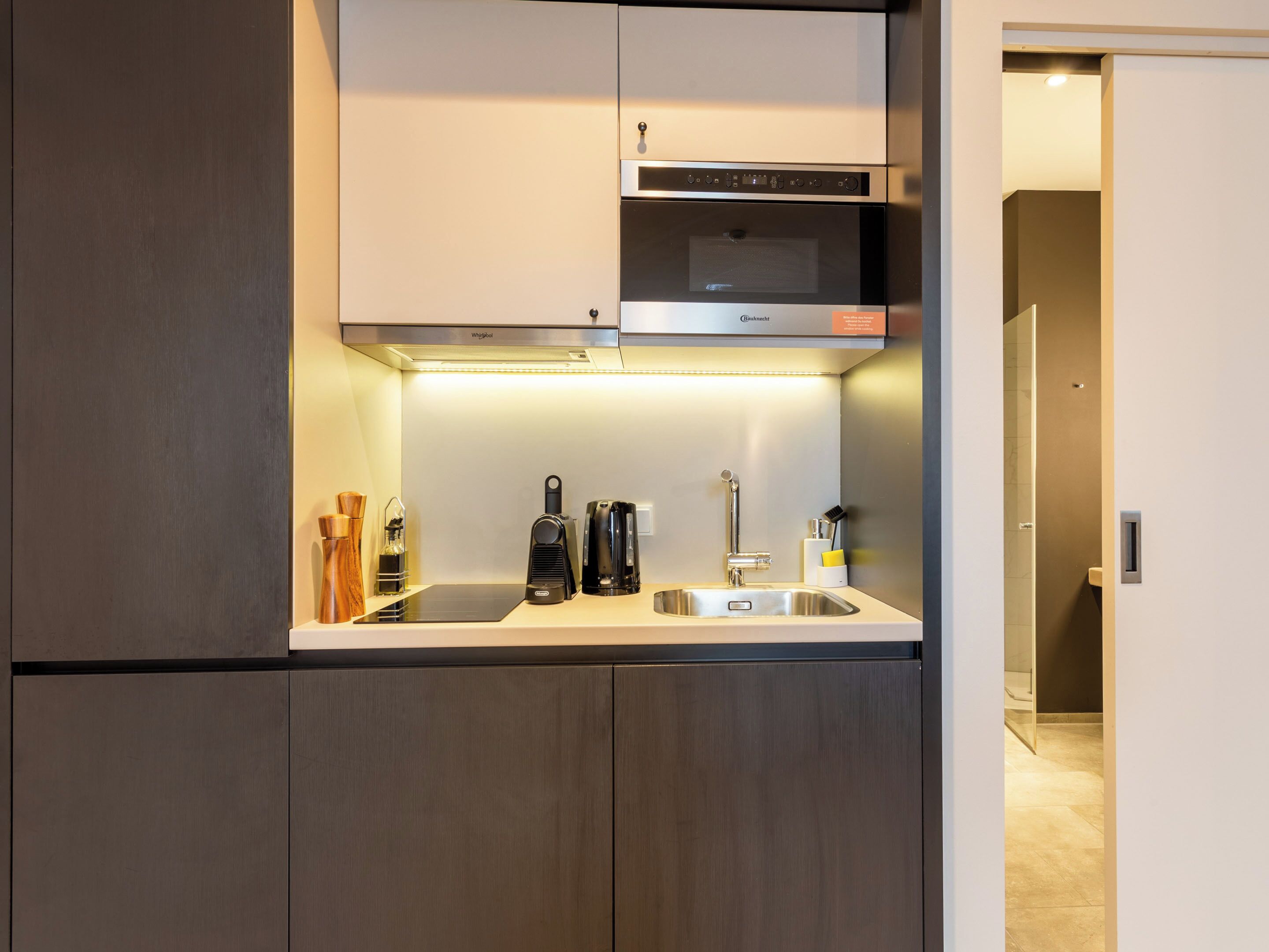 Una cocina moderna con microondas integrado, pileta de acero inoxidable y una mesada compacta.