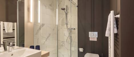 A modern bathroom with a glass-enclosed shower, a white sink, and a toilet.