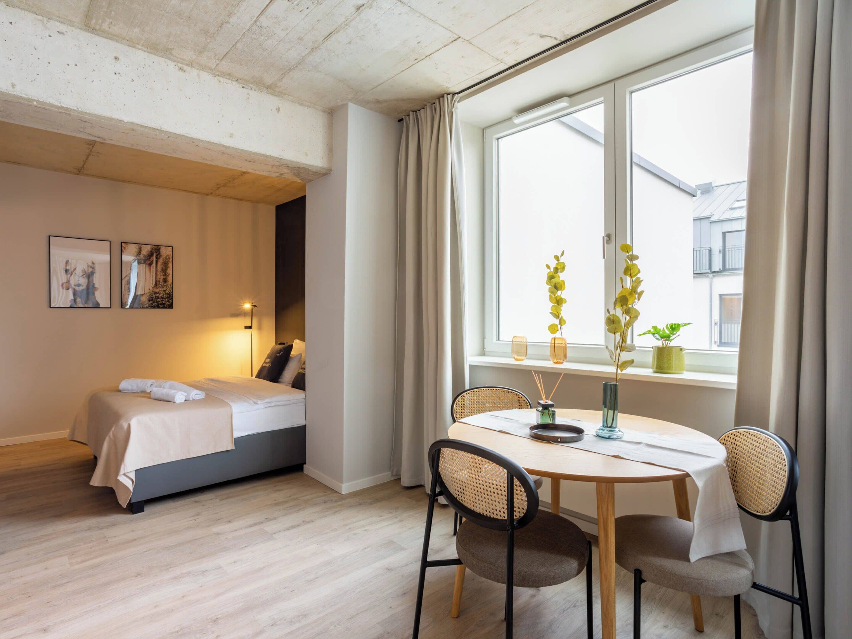 A bedroom with a bed, bedside table, and a window with curtains.